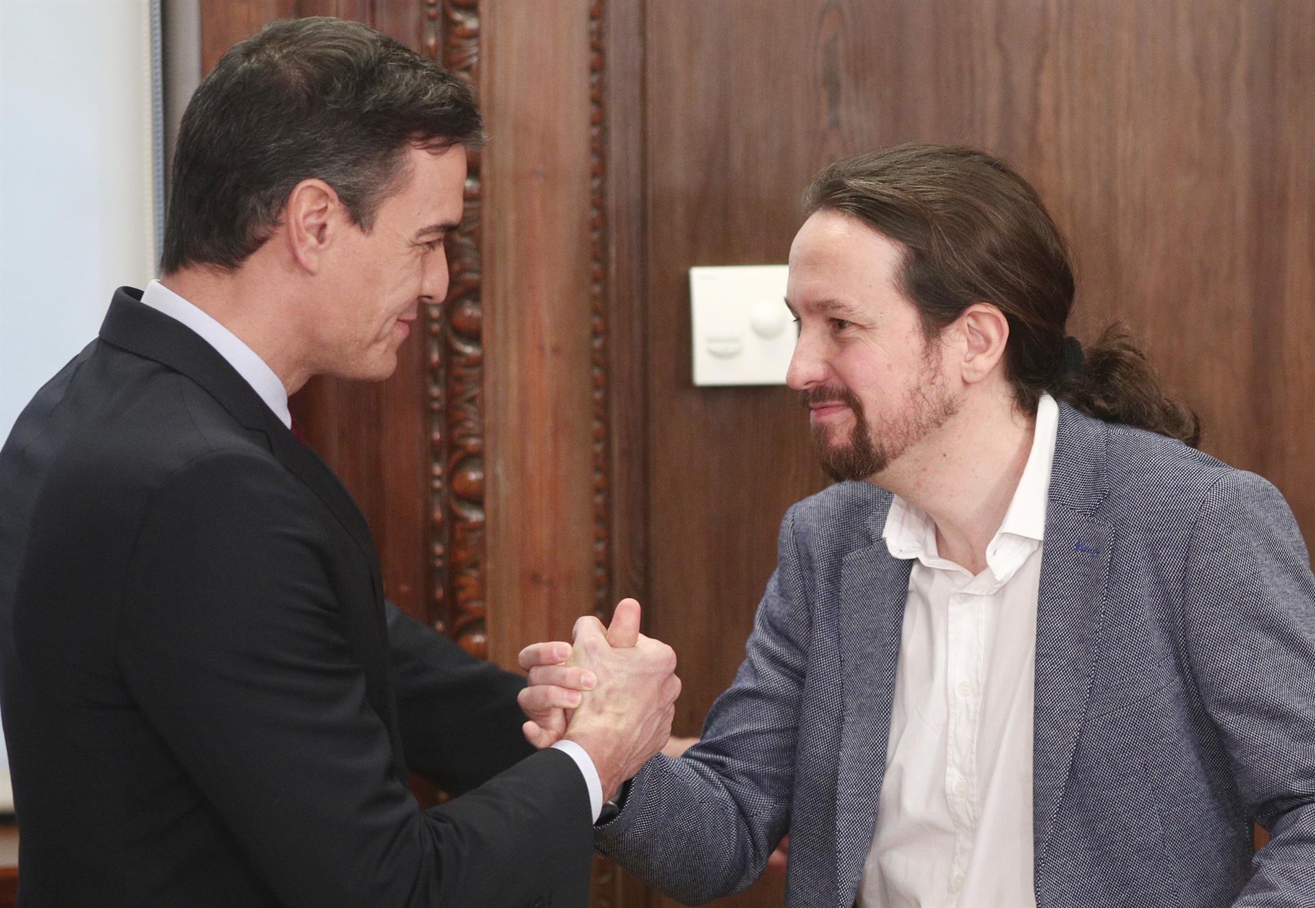 El presidente del Gobierno en funciones, Pedro Sánchez, y el secretario general de Podemos, Pablo Iglesias, se saludan tras presentar su acuerdo de gobierno en el Congreso de los Diputados / Europa Press