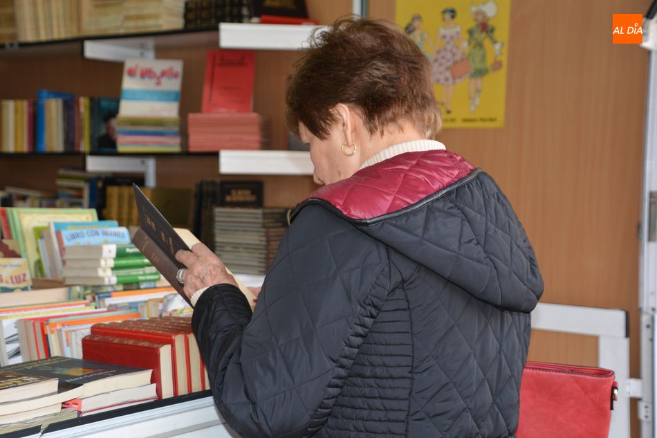 En la imagen, una mujer ojeando el ejemplar de un libro en la Feria del Libro de Salamanca