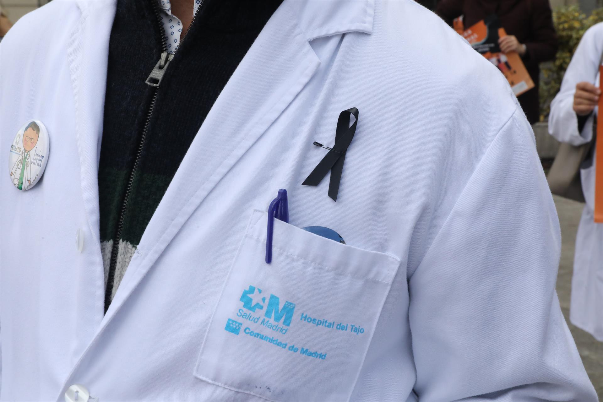 Detalle de un lazo negro colgado en la bata de un médico