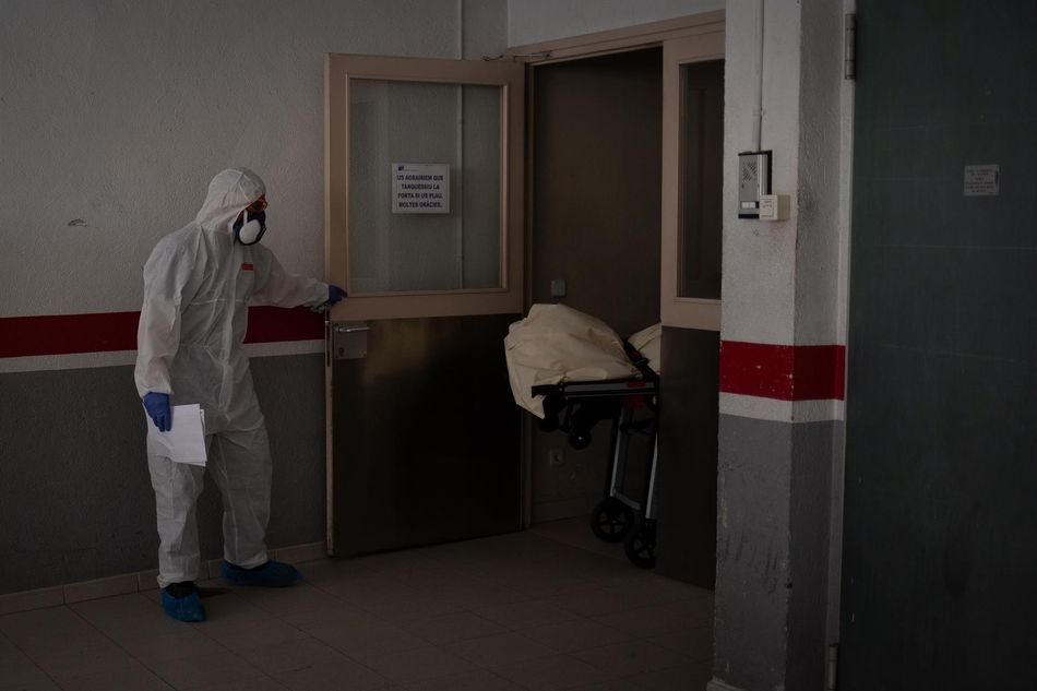 Varios operarios protegidos de los servicios funerarios trasladan el cuerpo de una persona fallecida en una residencia de ancianos de Girona durante la pandemia