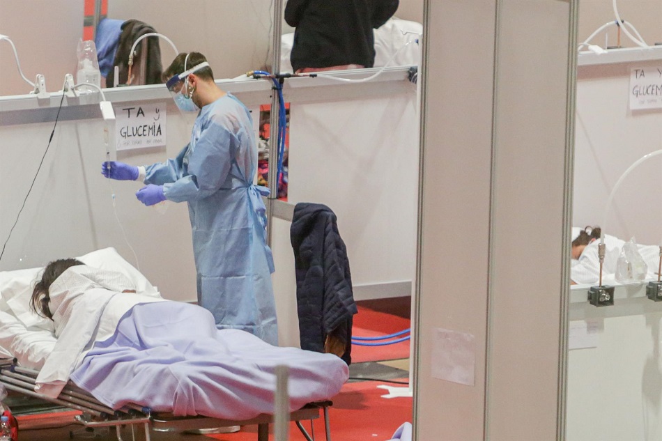Un sanitario protegido con mascarilla atiende a una paciente ingresada por coronavirus | EP